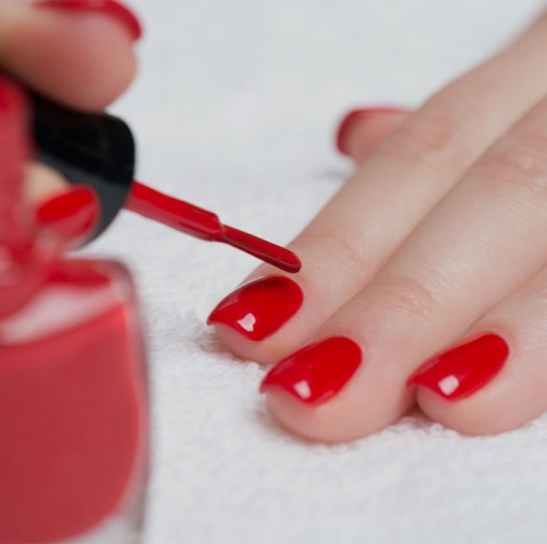 Red nail polish being applied to nails